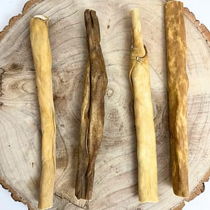 Set of 4 Goat Skin Rolls Natural dog treats displayed on a tree stump