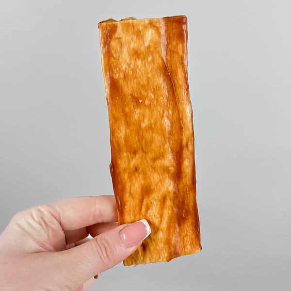 Chewllagen Chicken Chips Hand 1000 6"x2" flat Collagen dog chew being held by a female hand