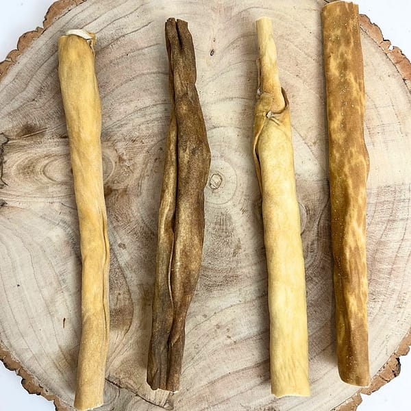 Set of 4 Goat Skin Rolls Natural dog treats displayed on a tree stump