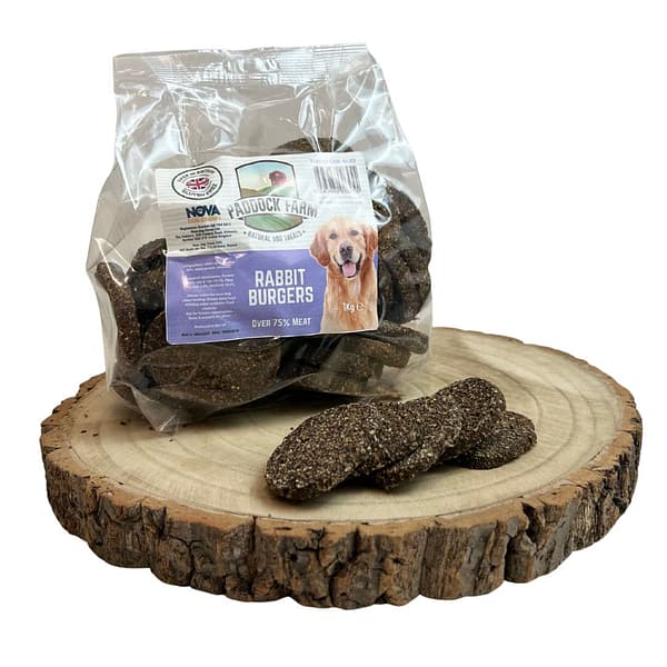 Pack of Rabbit burger dog treats displayed on a log with some loose in front