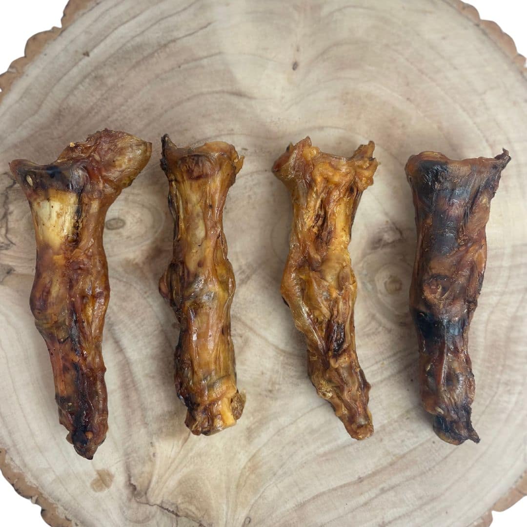 Large Ostrich Feet for Dogs – Hypoallergenic Long Lasting Dog Chew 2 Four Large Ostrich Feet arranged on a wooden slice – natural hypoallergenic long lasting dog chews rich in protein and calcium